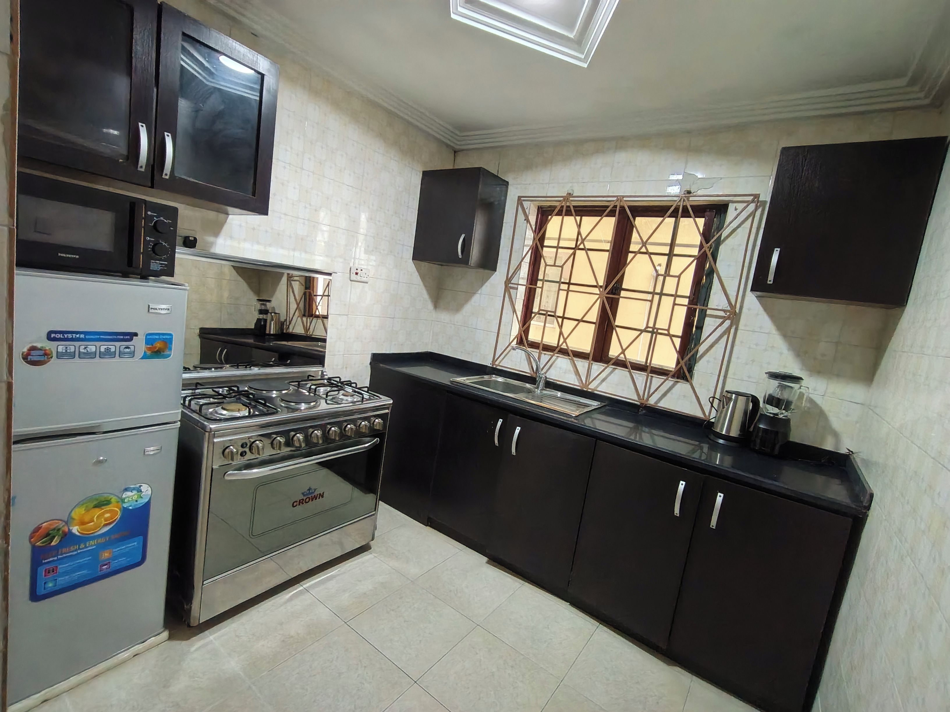 A kitchen with a gas stove, microwave, refrigerator, and black cabinets.