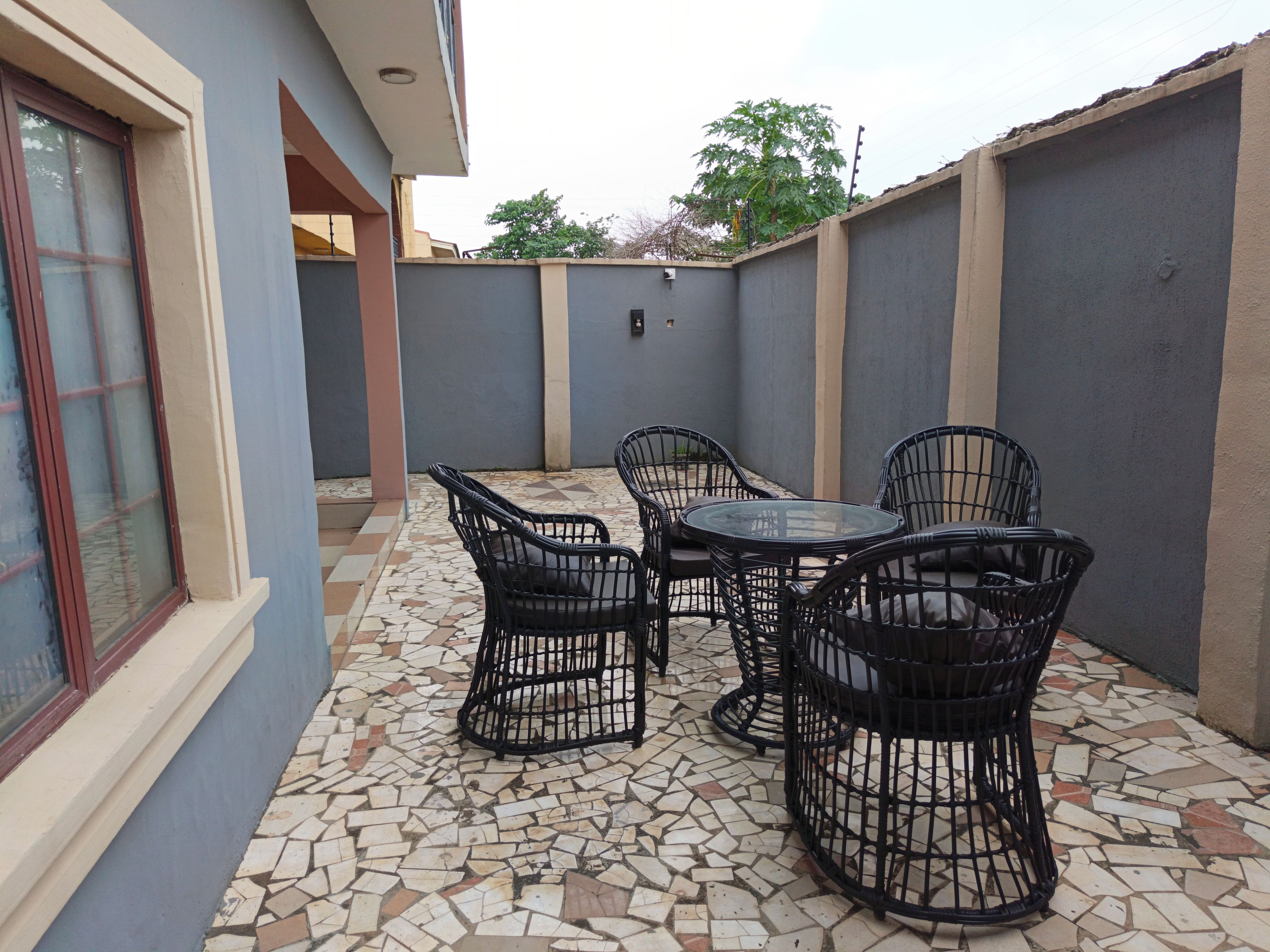 Un patio al aire libre con suelo de mosaicos, una mesa y cuatro sillas.