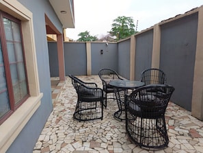 Pátio externo com piso em mosaico, uma mesa e quatro cadeiras.