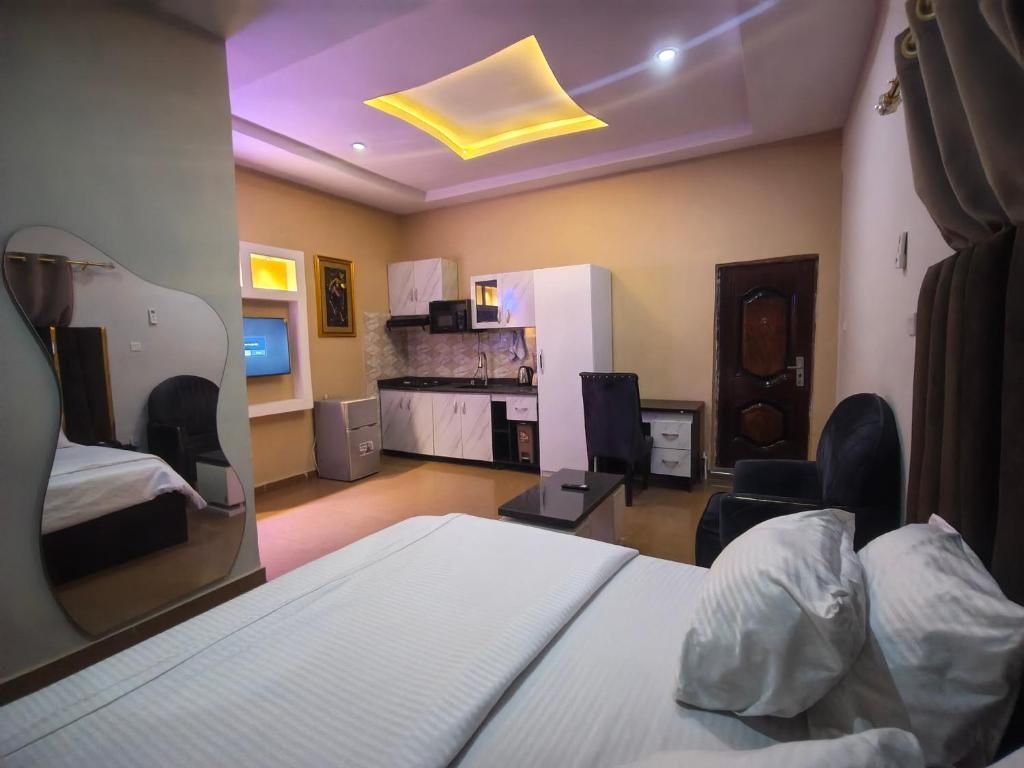 A hotel room with a bed, a desk, a chair, a TV, a microwave, and a small kitchenette.