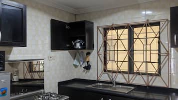 Una cocina con estufa a gas, horno, gabinetes negros, un lavamanos y una ventana con un diseño geométrico.