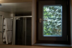 A bathroom with a towel rack and a glass door leading to a room with a view of trees.