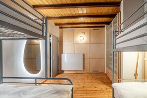 A compact room with bunk beds, a wooden floor, and a central light fixture.