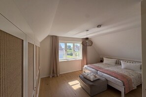 A bedroom with a bed, a window, and a hanging light fixture. - Zanzibar under a thatched roof (Ostseebad Rerik)