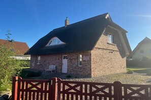 A small brick house with a steeply pitched roof, a white door, and a small window. - Zanzibar under a thatched roof (Ostseebad Rerik)