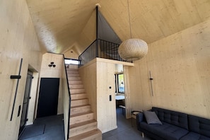 En interiör med träinredning, en trappa, en soffa och en hängande lampa.