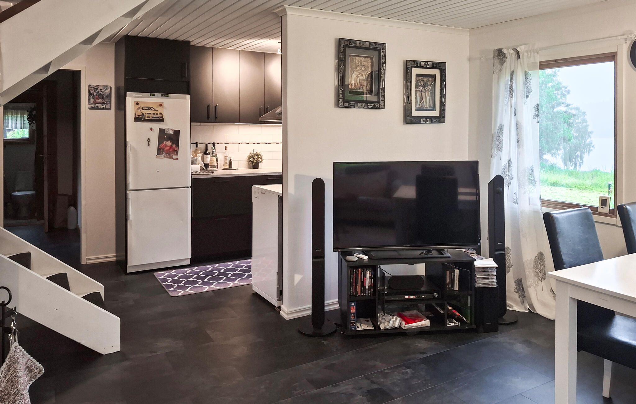 Ett kompakt bostadsutrymme med ett kök, en matplats och ett TV-bord med böcker.