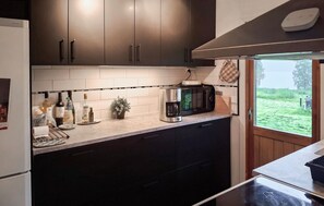 A kitchen with dark cabinets, a coffee maker, and a view of the outdoors.