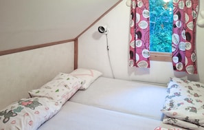 A bedroom with two single beds, a window with patterned curtains, a security camera, and a wooden ceiling beam. - Beautiful home in Degernäs with WiFi (Degernäs)