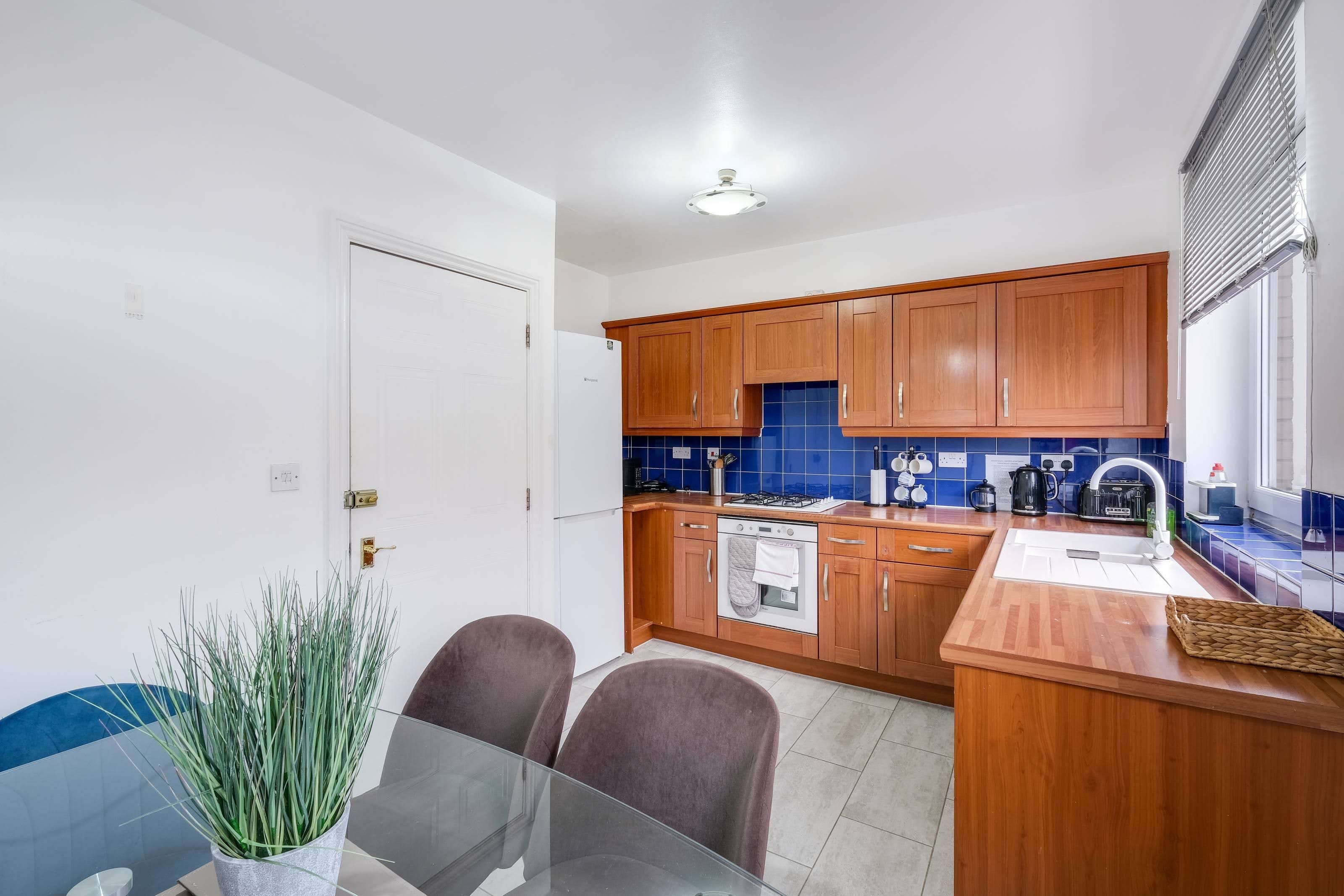Una cocina moderna con armarios de madera, cocina a gas y salpicadero de azulejos azules.