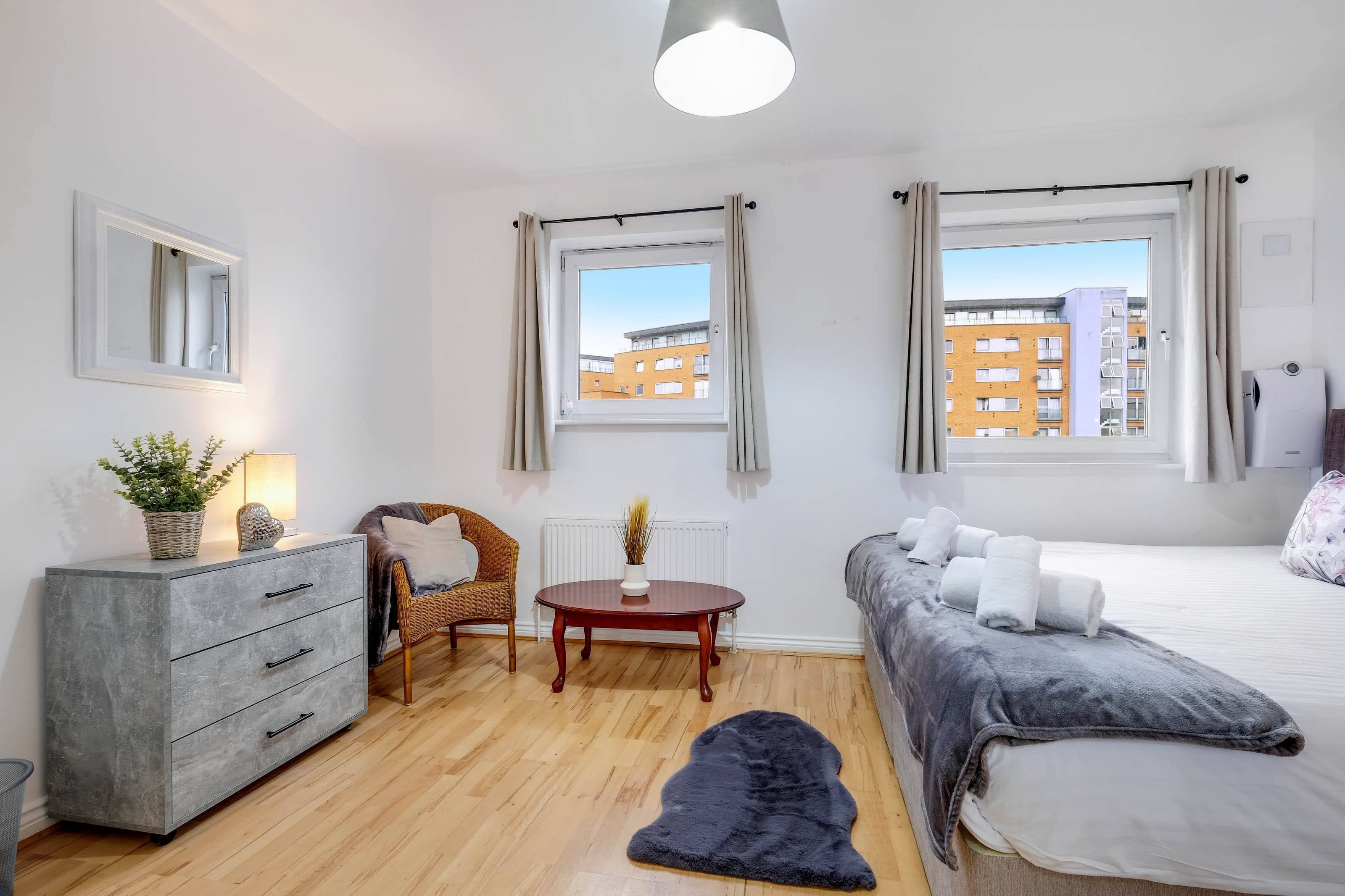A modern bedroom with a bed, a sofa, a dining table, and a dresser.