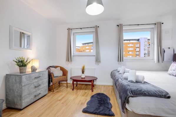 Un dormitorio moderno con cama, sofá, mesa de comedor y cómoda.