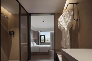 Un baño moderno con ducha, bañera y lavabo. Una ventana grande ofrece vistas de la ciudad.