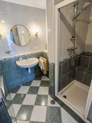 Un baño con lavamanos, espejo y ducha.