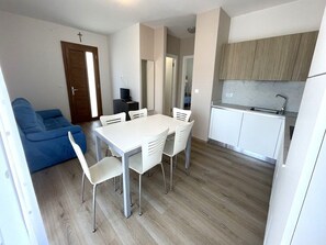A compact living space with a dining table, chairs, a sofa, and a kitchenette. - Serenity accommodation by the sea (Bibione)