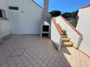 Un bâtiment à l’extérieur blanc, doté d’un sol carrelé et d’un escalier avec une rampe rouge.
