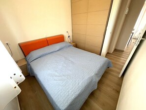 A single bed with an orange headboard in a room with wooden flooring and a tiled wall. - Serenity accommodation by the sea (Bibione)