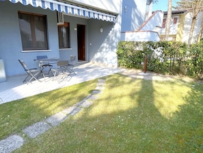 Ein Wohnhaus mit Terrasse, Gartenmöbeln und einem gepflegten Rasen.