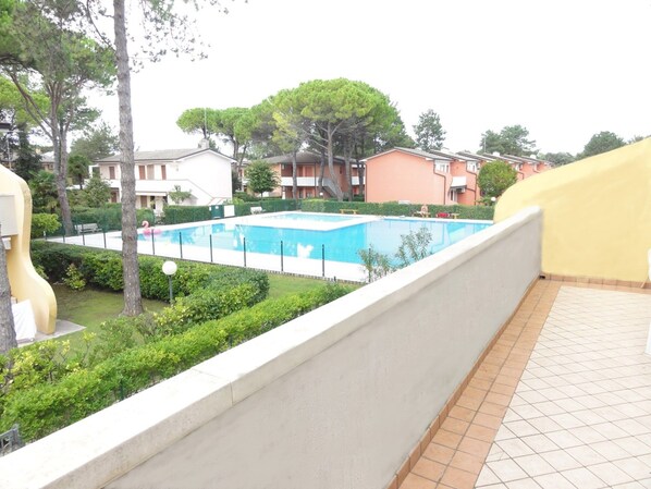 Piscina cercada por vegetação e edifícios.