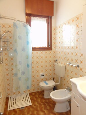 Casa de banho com chuveiro, sanita, bidé e lavatório.