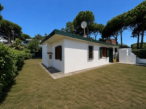 A small, single-story house with a green roof, a small front porch, and a satellite dish. - Holiday home with garden in Bibione Pineda (Bibione Pineda)