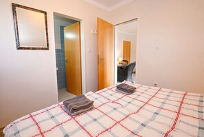 A hotel room with a bed, a mirror, and a door leading to a bathroom. - Cozy Vacation Rental 1 at Haus Kuhlmann (Büsum)