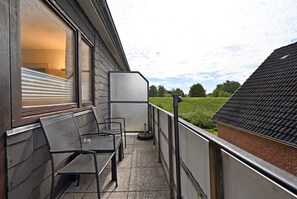 A balcony with two chairs and a table, overlooking a green landscape. - Cozy Vacation Rental 1 at Haus Kuhlmann (Büsum)