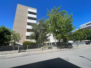 A multi-story building with a modern architectural style, a clear sky, and a tree-lined street. - Seaside comfort accommodation near the sea (Bibione)