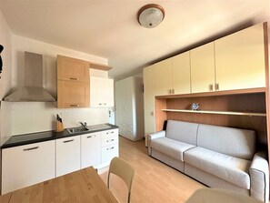 Una cucina compatta con mobili bianchi, un piano di lavoro in legno e una cappa aspirante integrata.