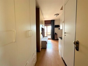 A hallway leading to a living area with a sofa and a television. - Sea breeze studio just 200 mt from the sea (Bibione)