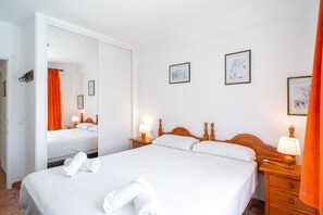 A hotel room with a large bed, two bedside tables with lamps, a mirror, and artwork on the walls. - Comfortable Apartment in Nerja (Nerja)