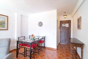 A dining area with a glass table and chairs, a small decorative plate on the wall, and a door with a notice. - Comfortable Apartment in Nerja (Nerja)