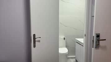 Een kamer met een bed, een witte deur naar een badkamer en een airconditioning unit erboven.