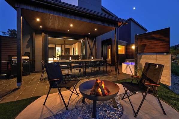 An outdoor patio with a fire pit, seating, and a grill area. - SUITE VILLA -AOI- (Takashima-shi)