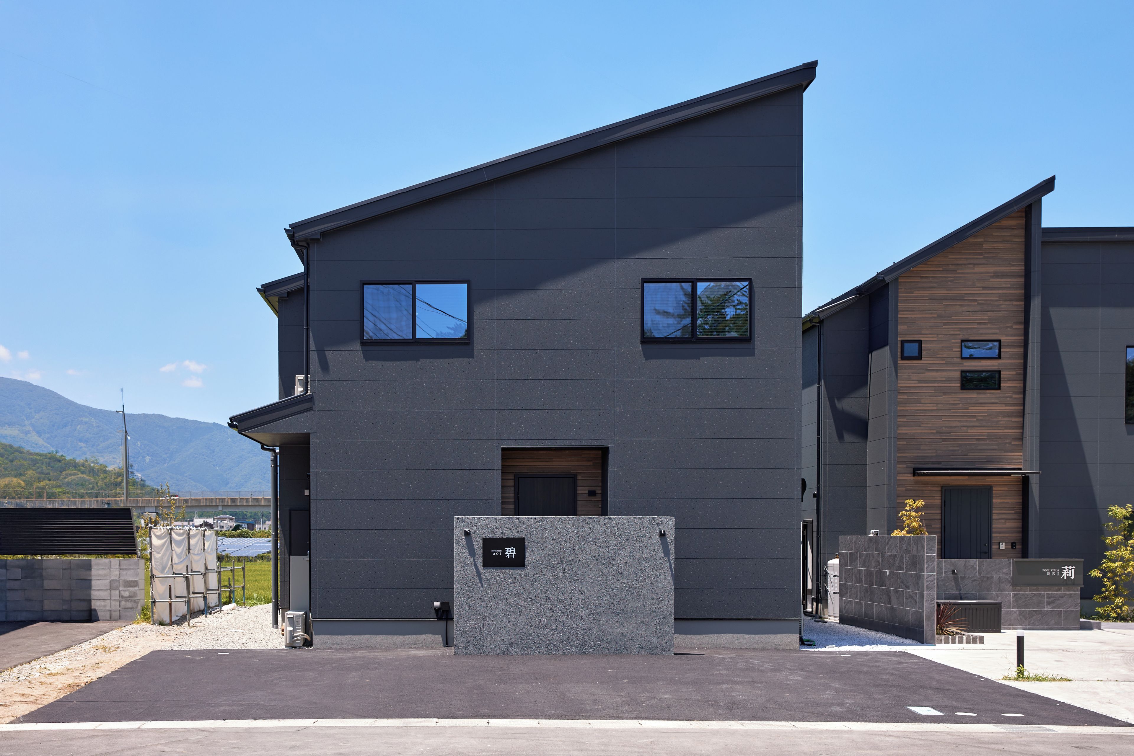 A modern two-story building with a flat roof, large windows, and a visible entrance.