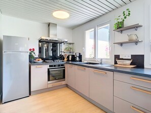 Une cuisine moderne dotée d’appareils électroménagers en acier inoxydable, de meubles en bois et d’une grande fenêtre qui laisse entrer la lumière naturelle.