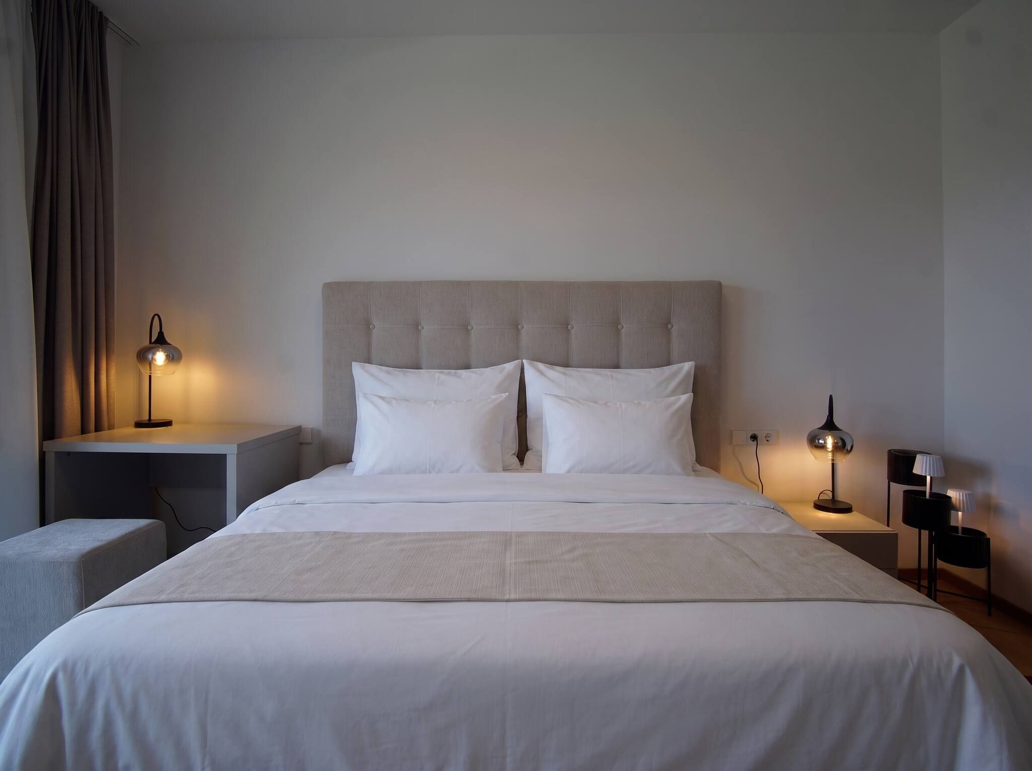Une chambre d’hôtel avec un grand lit, deux tables de chevet et deux lampes.