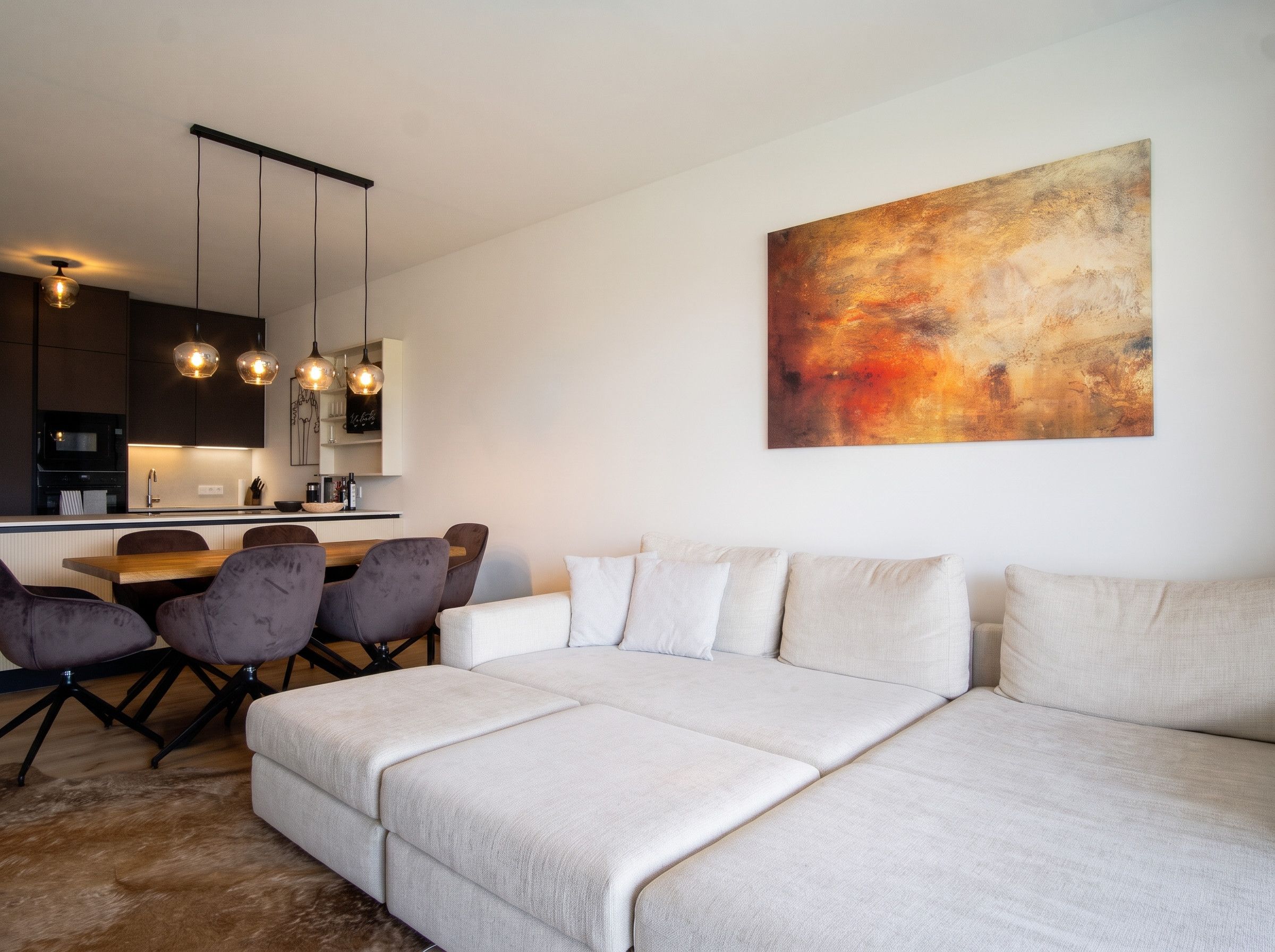 Een moderne woonkamer met een bank, stoelen en een eethoek.