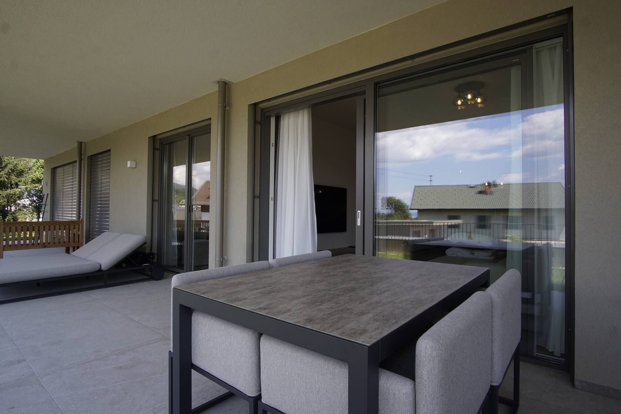 Un balcon avec une table et des chaises, un canapé et une porte-fenêtre coulissante donnant sur un espace extérieur.