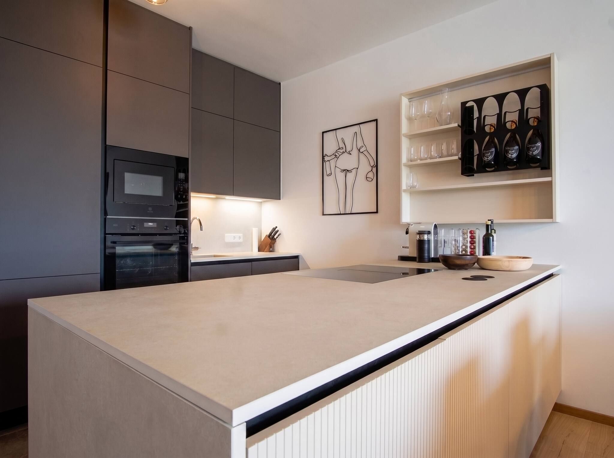 Eine moderne Küche mit Kochinsel, Einbauofen und Weinkühlschrank.