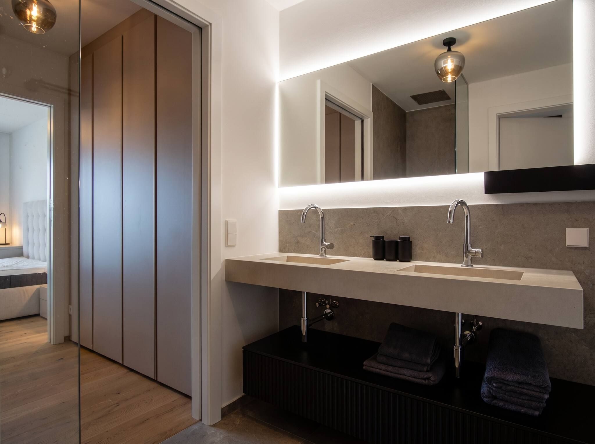Un baño moderno con un espejo grande, dos lavamanos y un perchero para toallas.