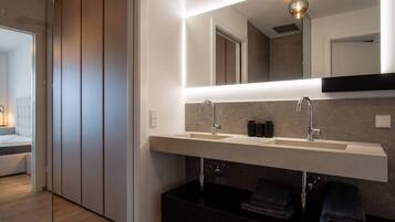 Un baño moderno con un espejo grande, dos lavamanos y un perchero para toallas.