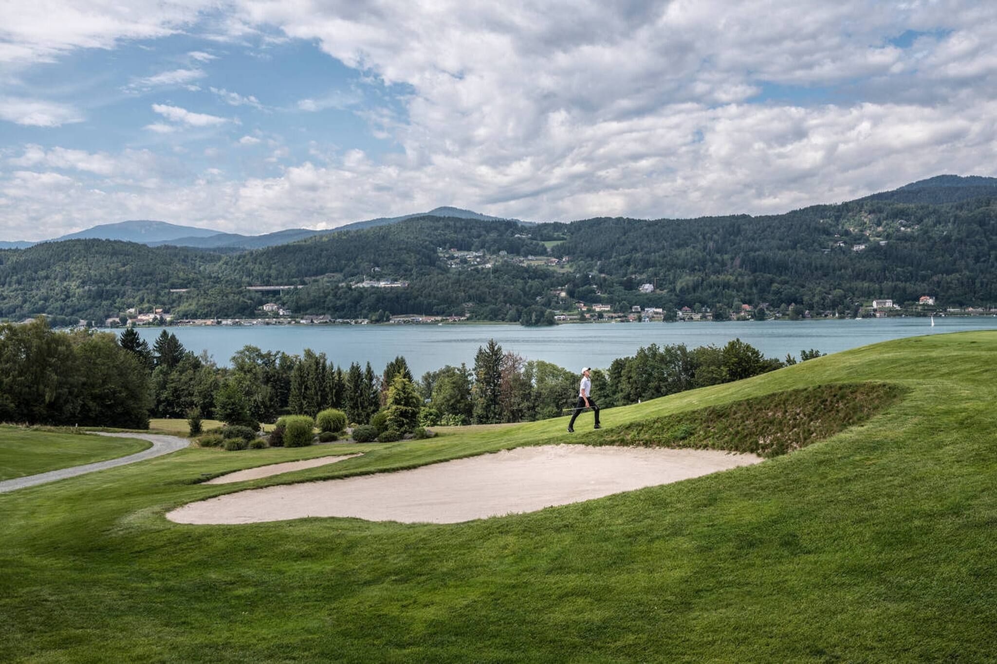A golf course with a lake and mountains in the background.
