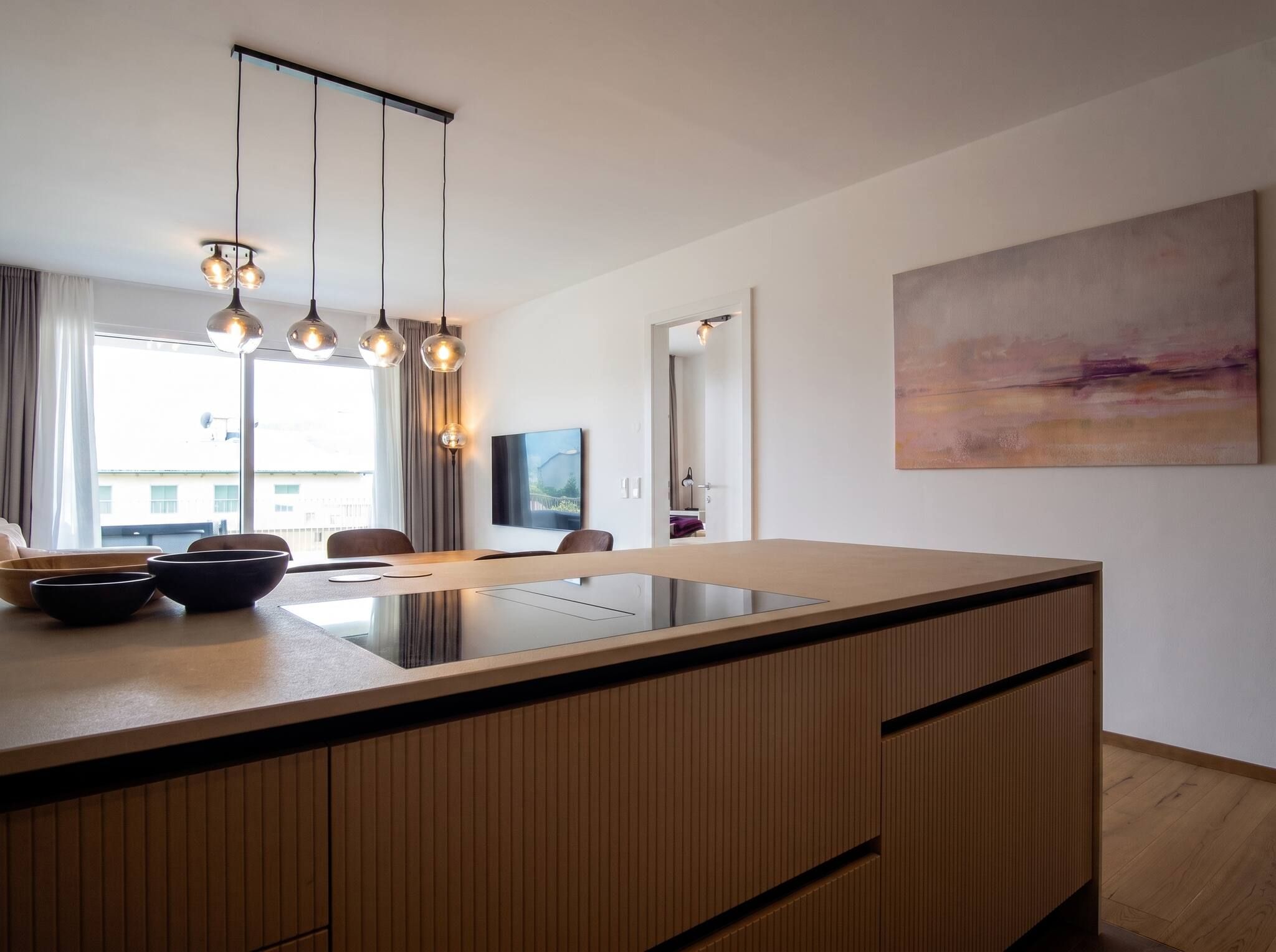 Une cuisine moderne dotée d’un îlot central, de luminaires suspendus et d’une grande fenêtre.