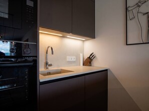 Una cocina moderna con horno empotrado, pileta de acero inoxidable y bloque para cuchillos.