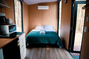 A compact room with a bed, a microwave, and a small table.