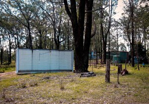 A large metal structure in a wooded area with trees and a dirt path.