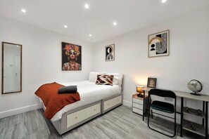 Un dormitorio moderno con cama, mesitas de noche, un escritorio y una silla.