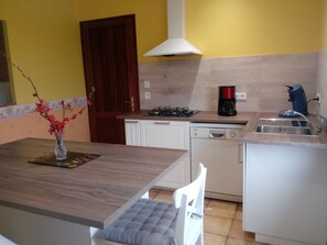 A compact kitchen with a dining area, a coffee maker, and a dishwasher. - Maison familiale, Proche Saint-Emilion (Pujols)