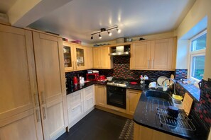 Una cocina con gabinetes de madera, una encimera negra y un salpicadero de azulejos.